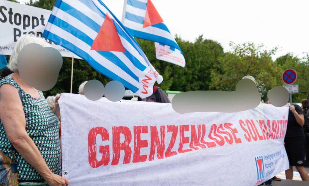 Demonstrationsteilnehmer*innen halten ein Banner mit der Aufschrift "grenzenlose Solidarität" hoch