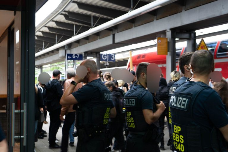 Am Bahnhof stehen einige Polizist*innen und empfangen die Demoteilnehmer*innen