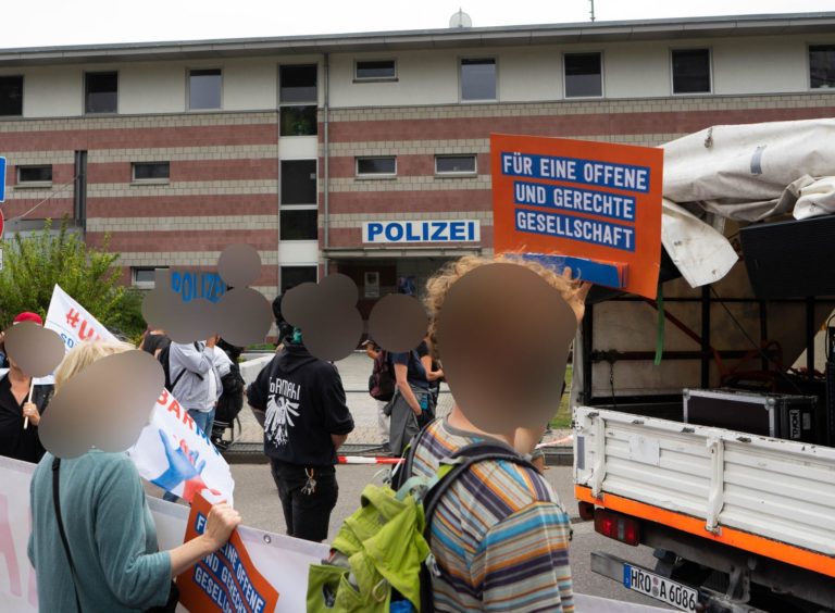Vor einer Polizeistation werden Plakate mit der Aufschrift "Für eine offene und gerechte Gesellschaft" hochgehoben