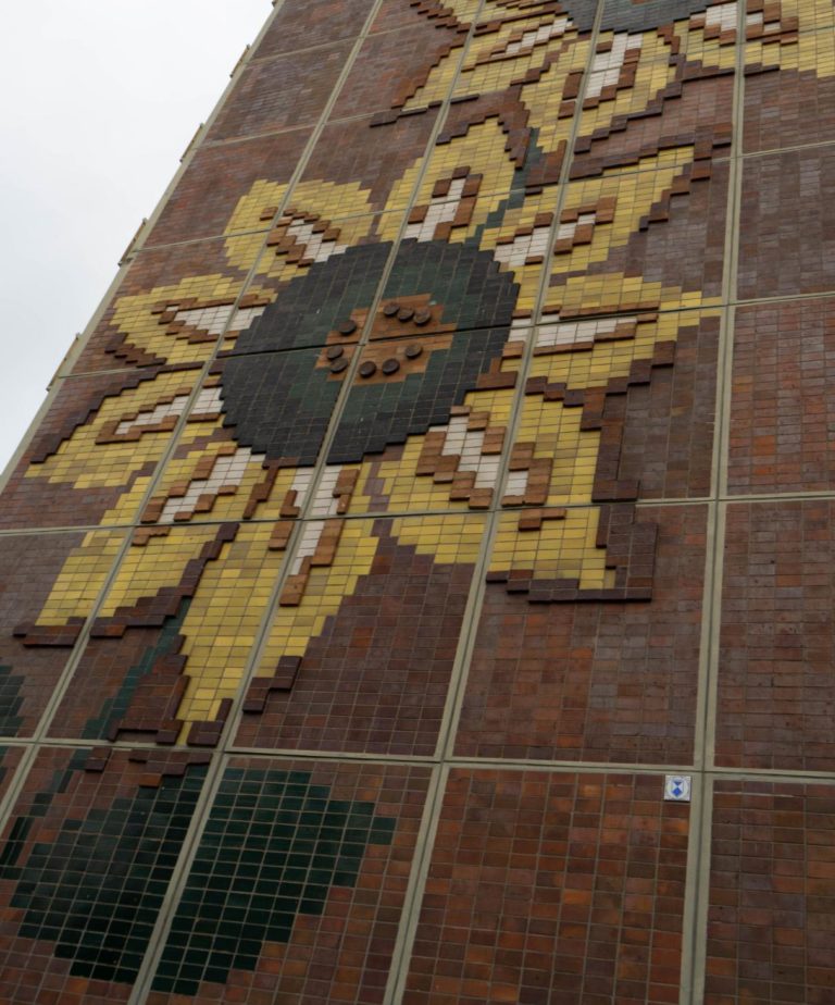 Eine Hausfassade, auf der sich ein Mosaik von Sonnenblumen befindet